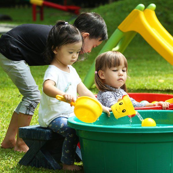 A boy and two little girls are playing in a sandbox