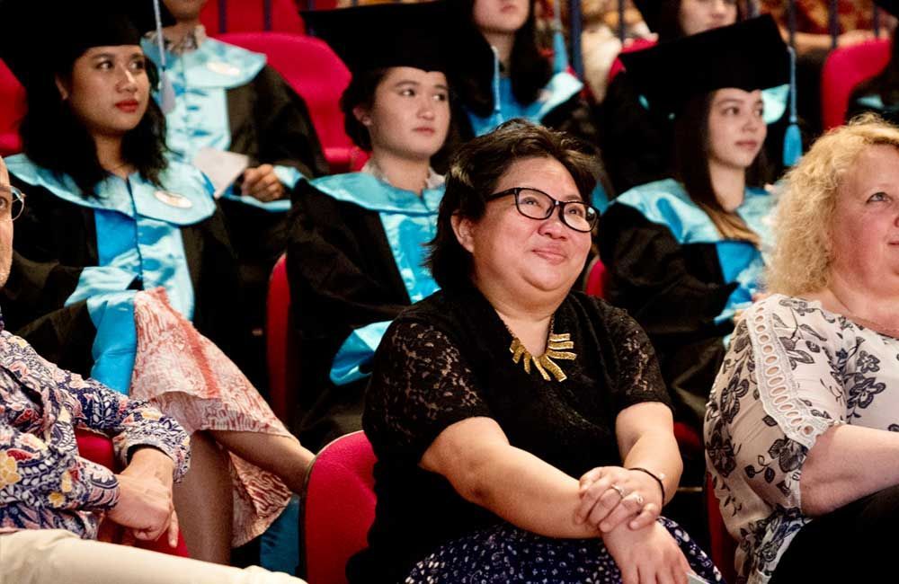 A group of women in graduation gowns are sitting in a theater.