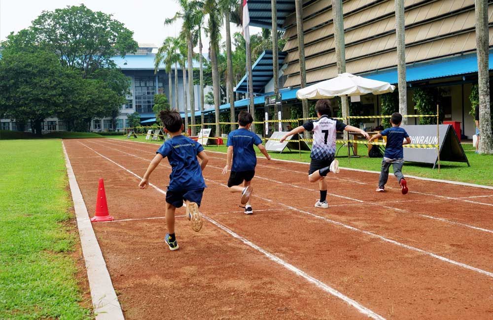A group of children are running on a track.