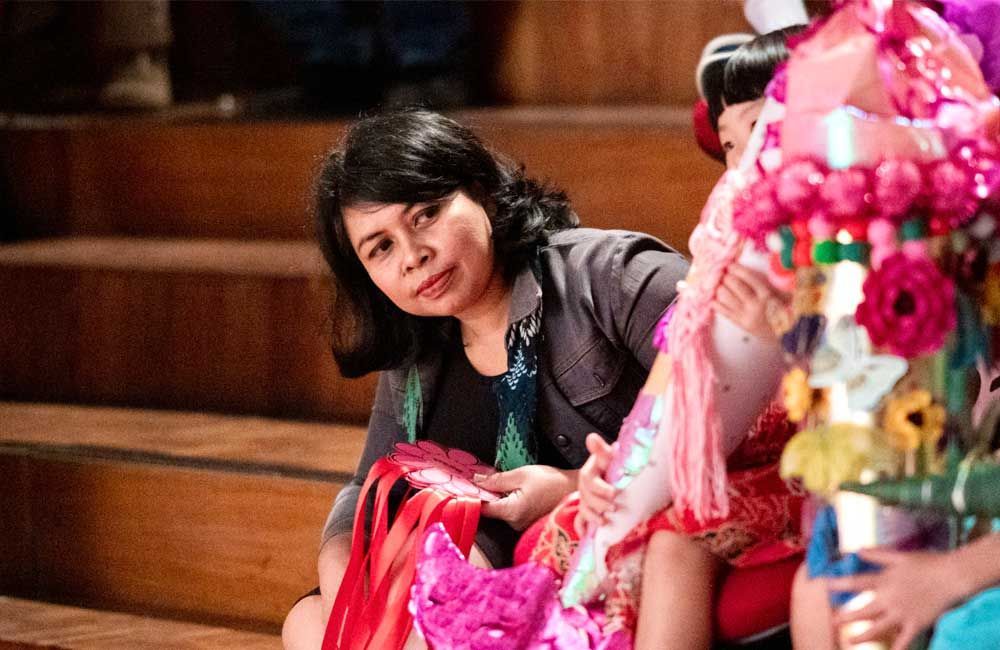 A woman is sitting on a wooden staircase next to a doll.