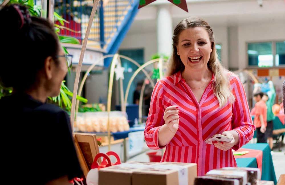 A woman in a red and pink striped shirt is talking to another woman.