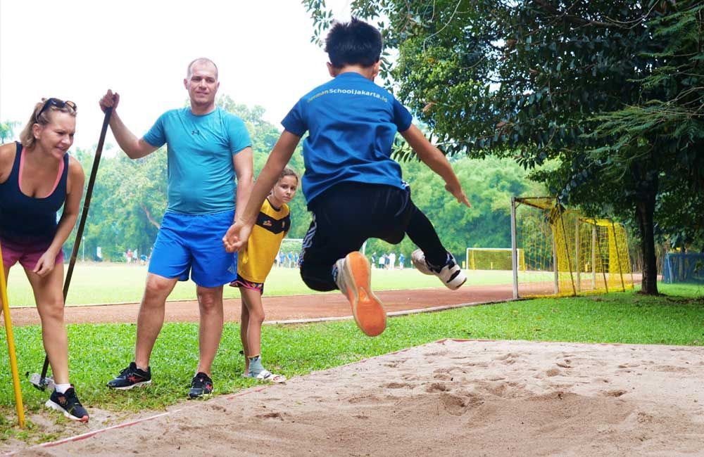 A boy is jumping in the air while a group of people watch.