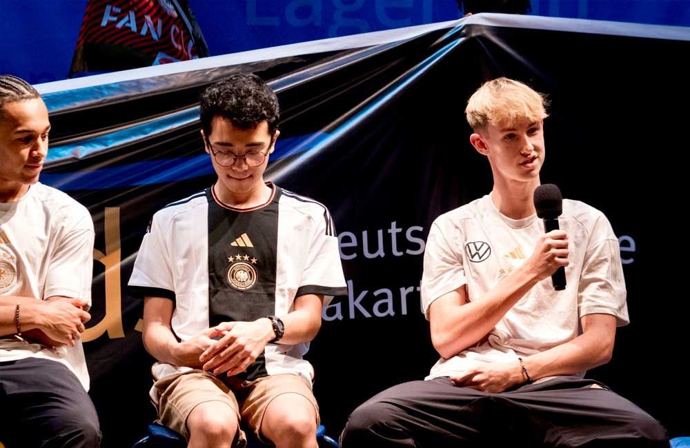 Three young men are sitting in front of a microphone.