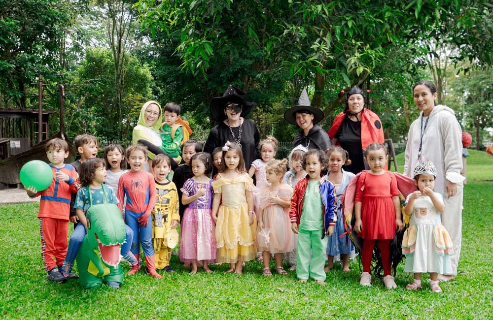 A group of children dressed in costumes are posing for a picture in a park.