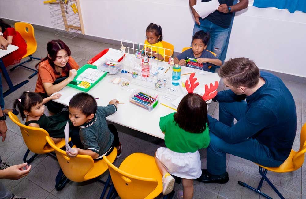 A group of children are sitting around a table in a classroom.