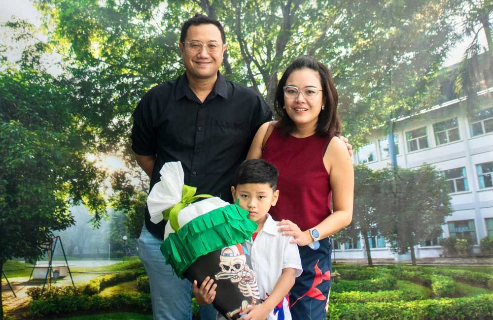 A family is posing for a picture in front of a green background.