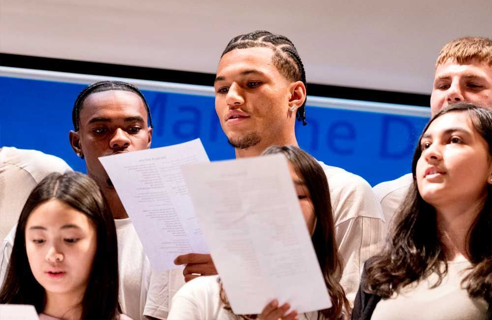 A group of people are singing in a choir with a blue background