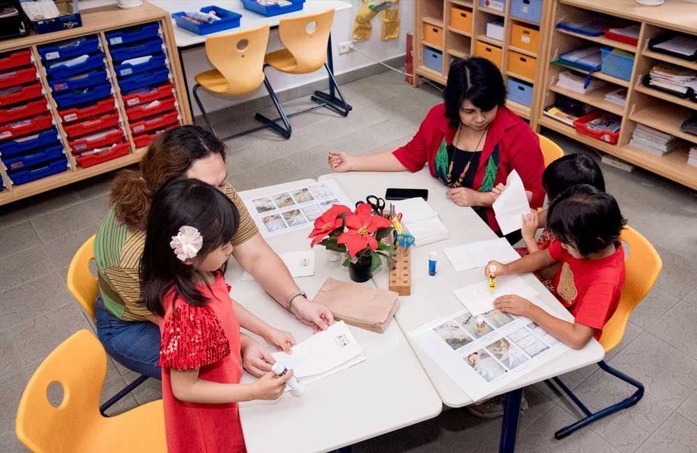 A group of people are sitting around a table in a classroom.