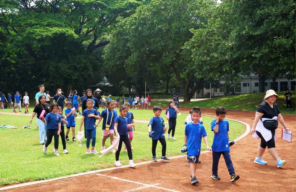 A group of children are walking on a track in a park.
