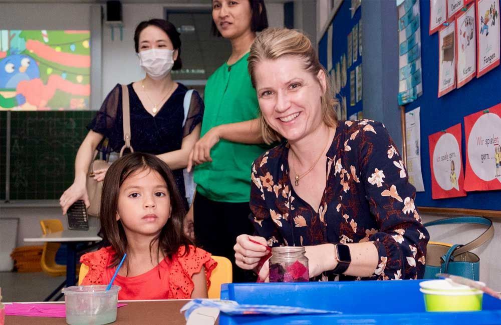 A woman is sitting next to a little girl in a classroom.