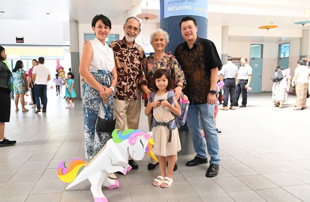 A group of people are posing for a picture with a unicorn balloon.