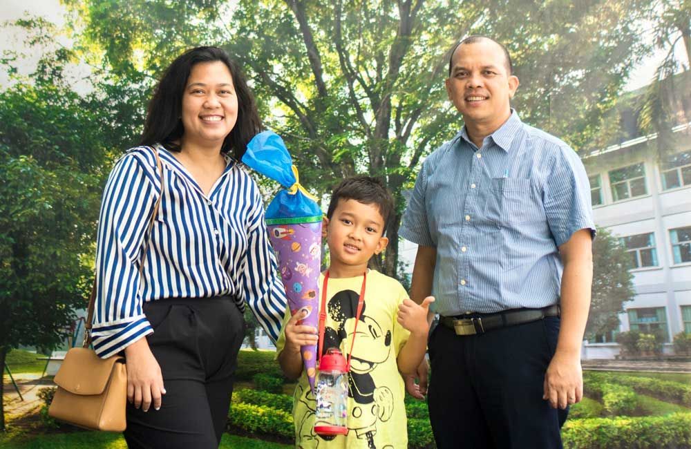 A family is posing for a picture with a child holding a cone.