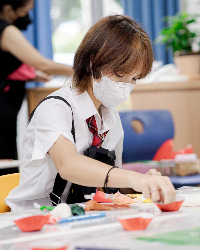 A woman wearing a mask is sitting at a table.