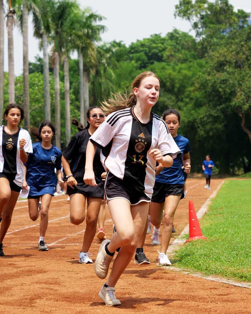 A group of girls are running on a track and one of them has the number 12 on her shirt