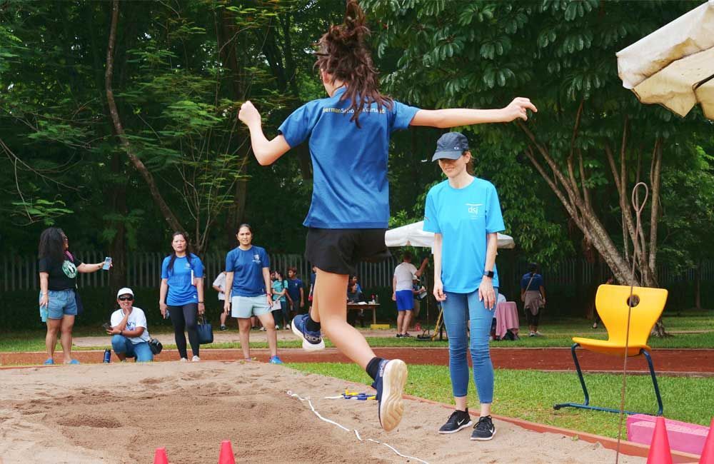 A girl is jumping in the air while a group of people watch.