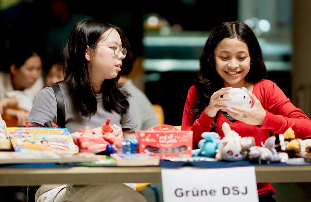 Two girls are sitting at a table holding stuffed animals.
