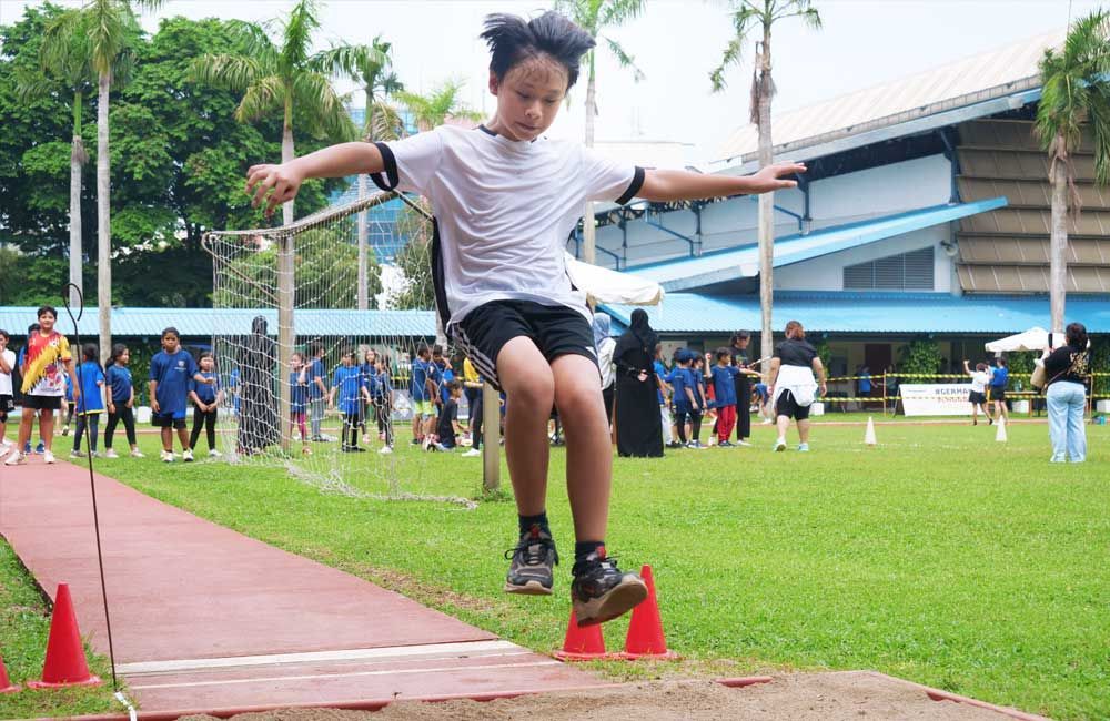 A young boy is jumping over cones on a track