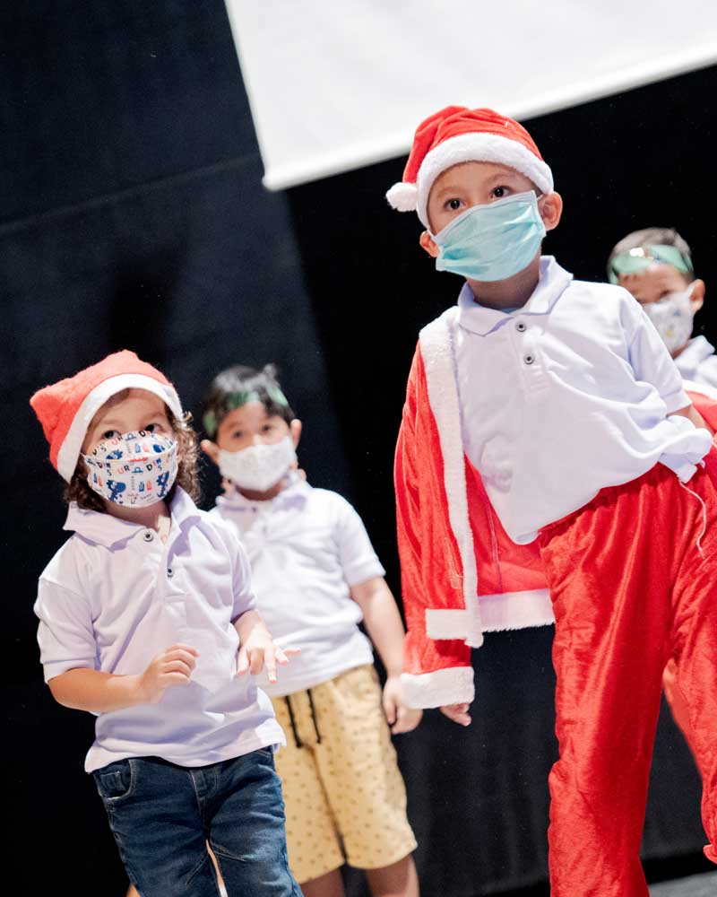 A group of children wearing face masks and santa hats
