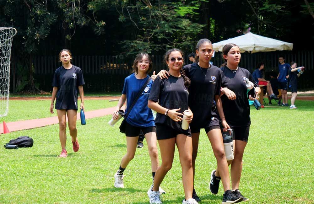 A group of young women are walking on a lush green field.