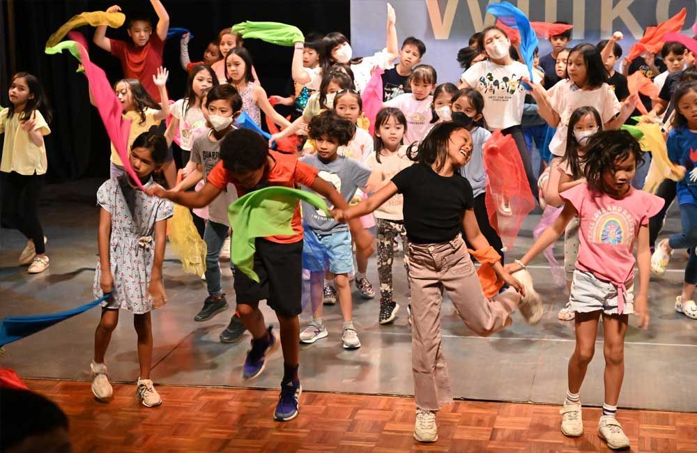 A group of children are dancing on a stage.