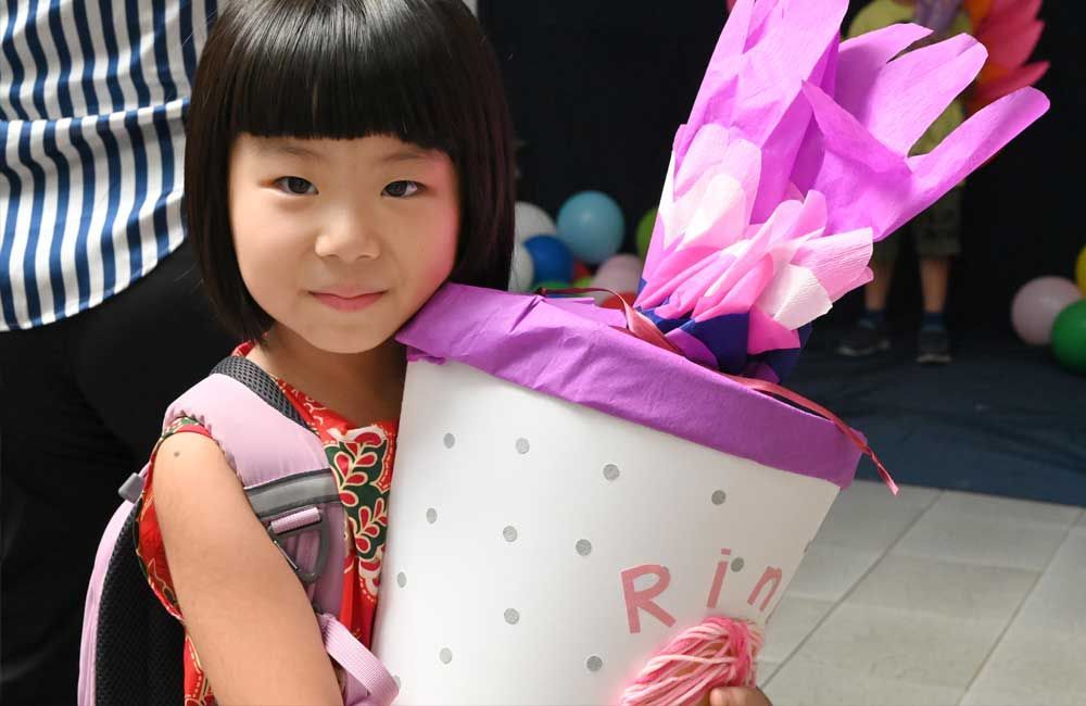 A little girl is holding a bucket with the letter r on it