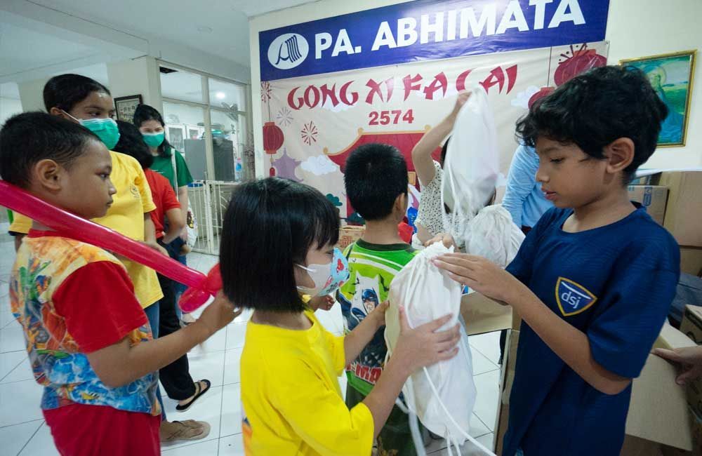 A group of children are standing in front of a sign that says pa abhimata.