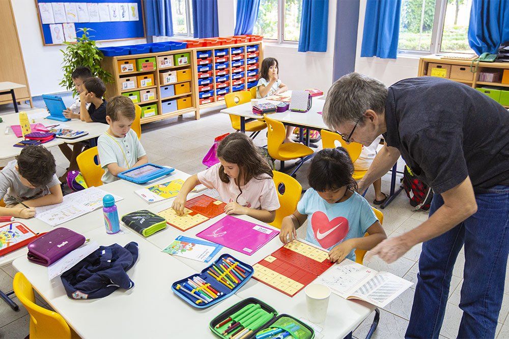 A German teacher helping his primary students during class at the German School Jakarta