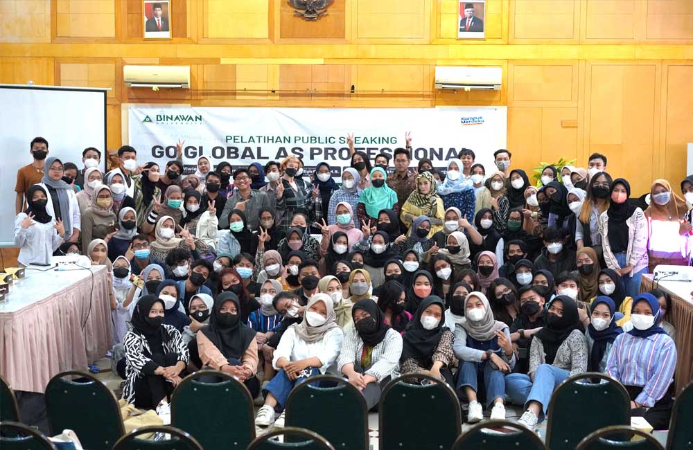 A large group of people wearing masks are posing for a picture in a room.