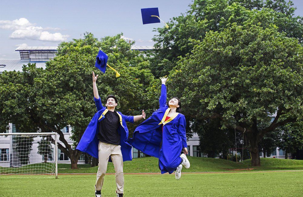 Two graduates of the German international Abitur jump in joy at the German School Jakarta campus