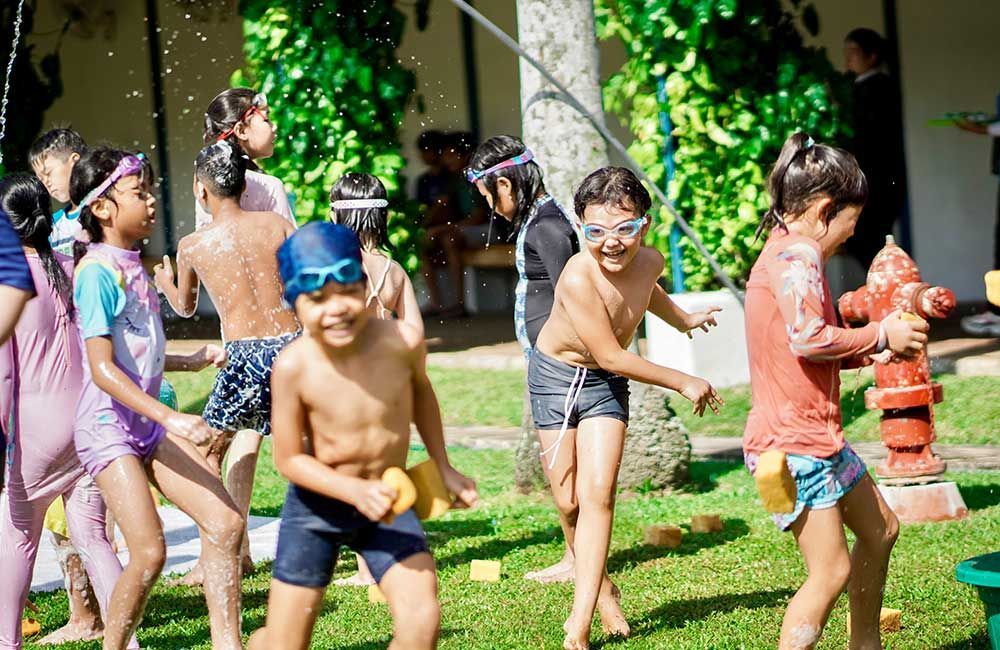 A group of children are playing with a fire hydrant in a yard.