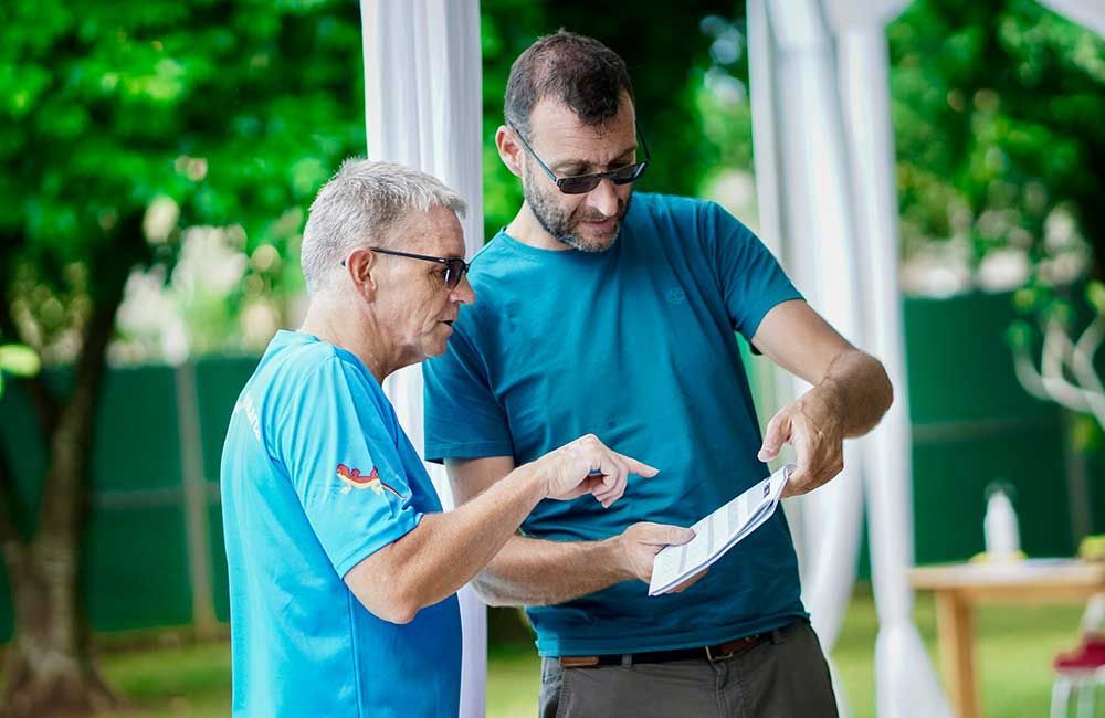 Two men are standing next to each other looking at a piece of paper.
