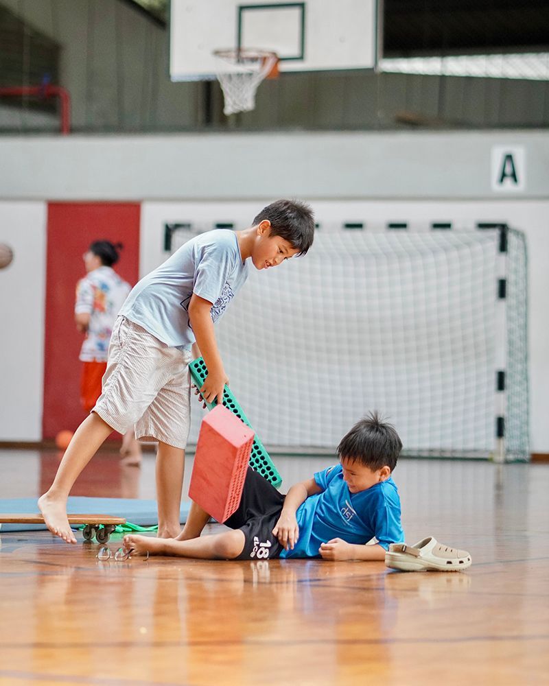 Two young boys are playing on a basketball court.