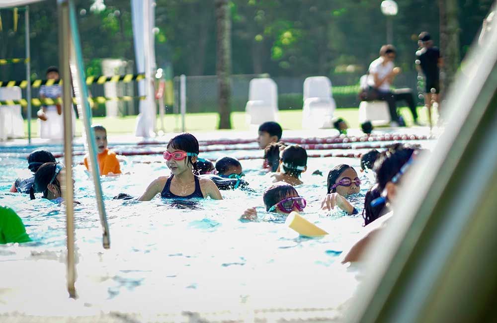 A group of children are swimming in a swimming pool.