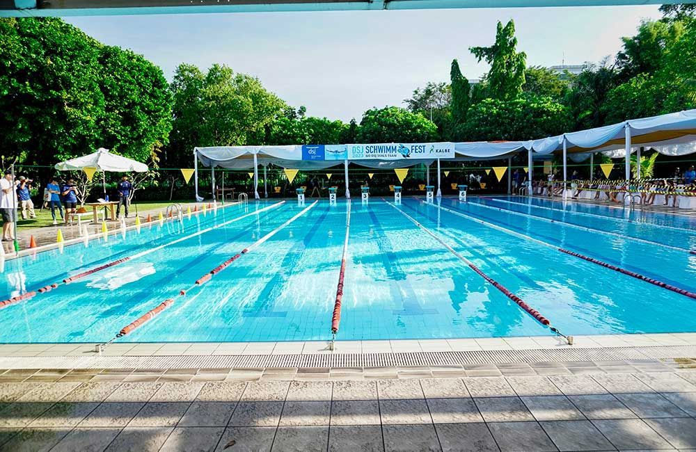 A large swimming pool surrounded by trees and people.