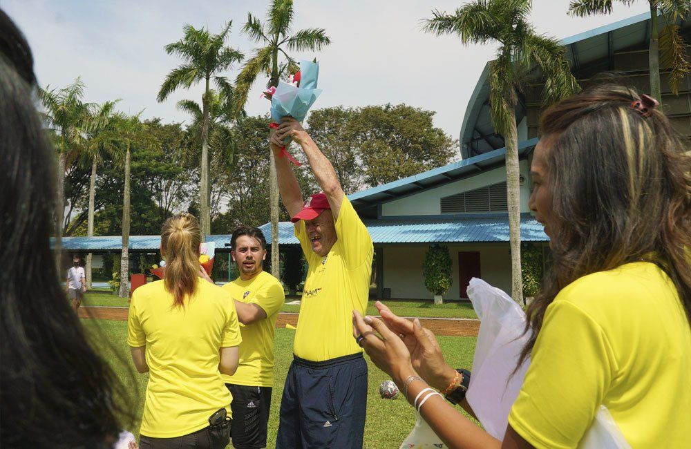 A group of people wearing yellow shirts are clapping in front of a building