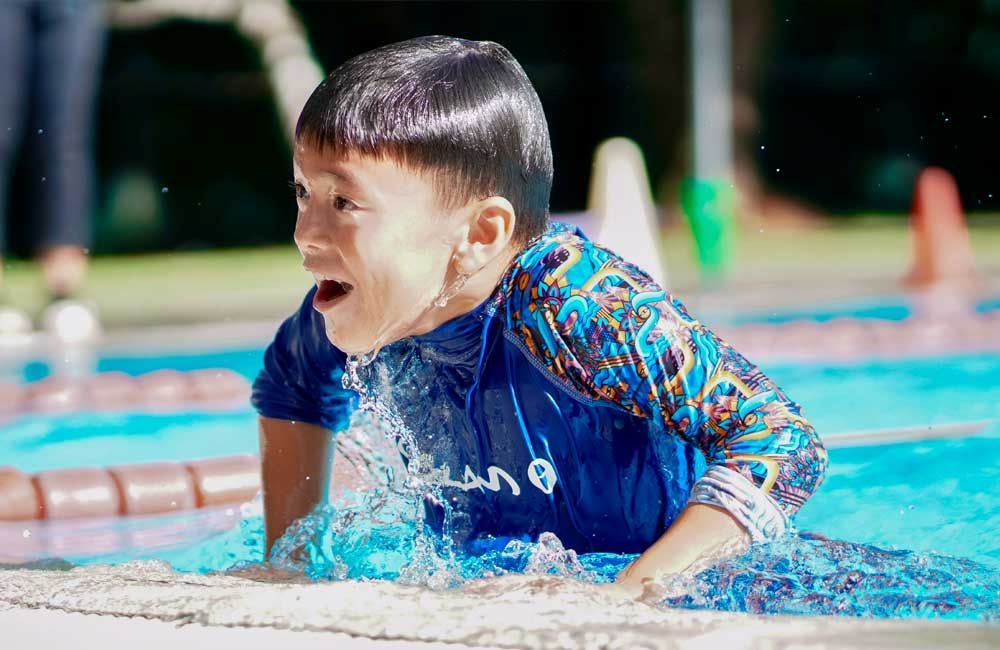 A young boy is playing in a swimming pool.