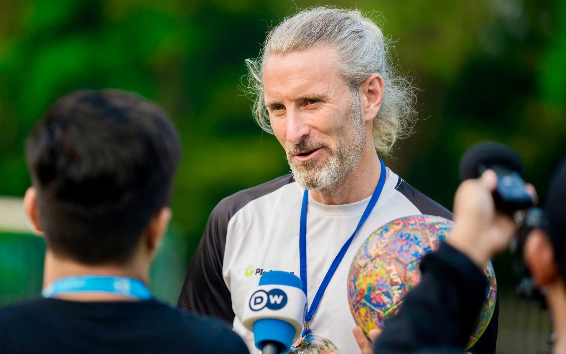 A man with a medal around his neck is talking into a microphone.