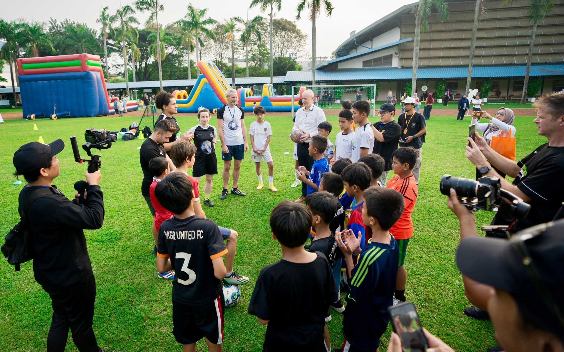 A group of children are standing in a circle on a soccer field.