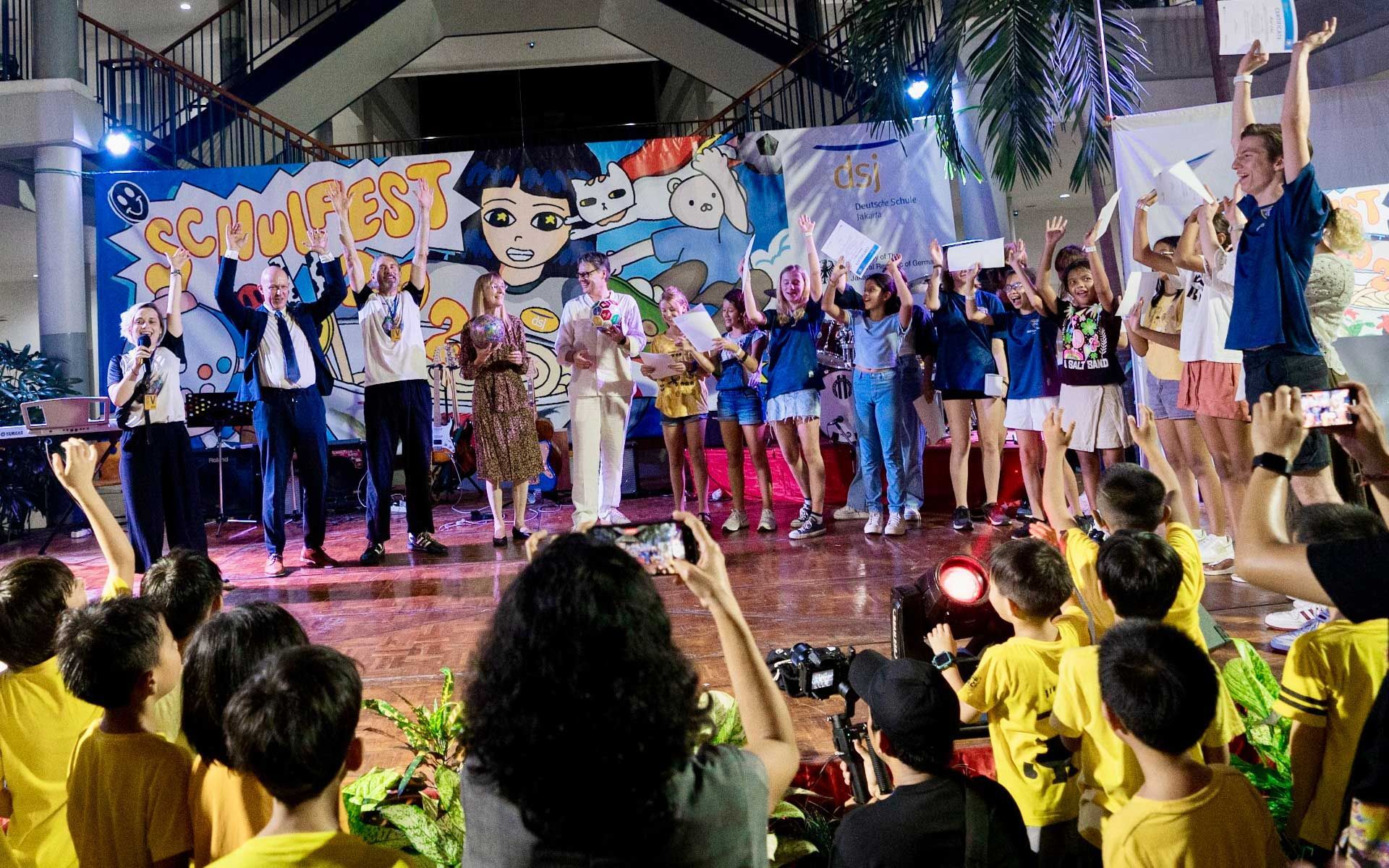 A group of people are standing on a stage in front of a crowd.