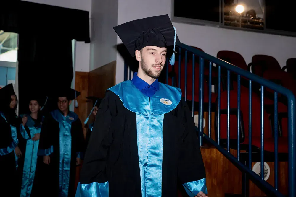 A man in a graduation cap and gown is walking down stairs