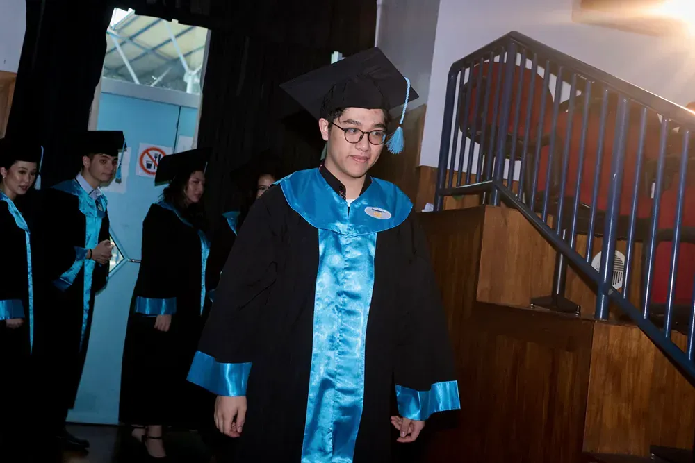 A man in a graduation cap and gown is walking down the stairs.