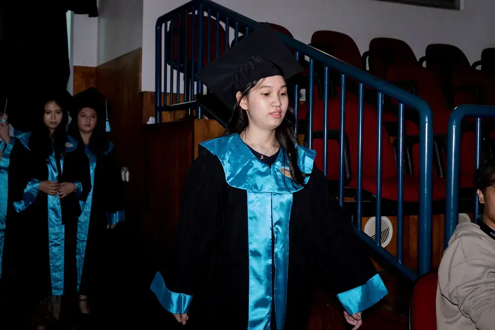 A woman in a graduation cap and gown is walking down stairs