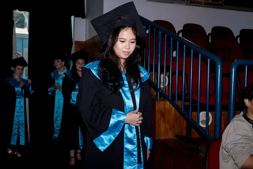 A woman in a graduation cap and gown is walking down the stairs