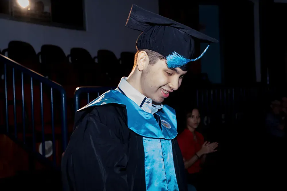 A man in a graduation cap and gown is walking down the stairs.