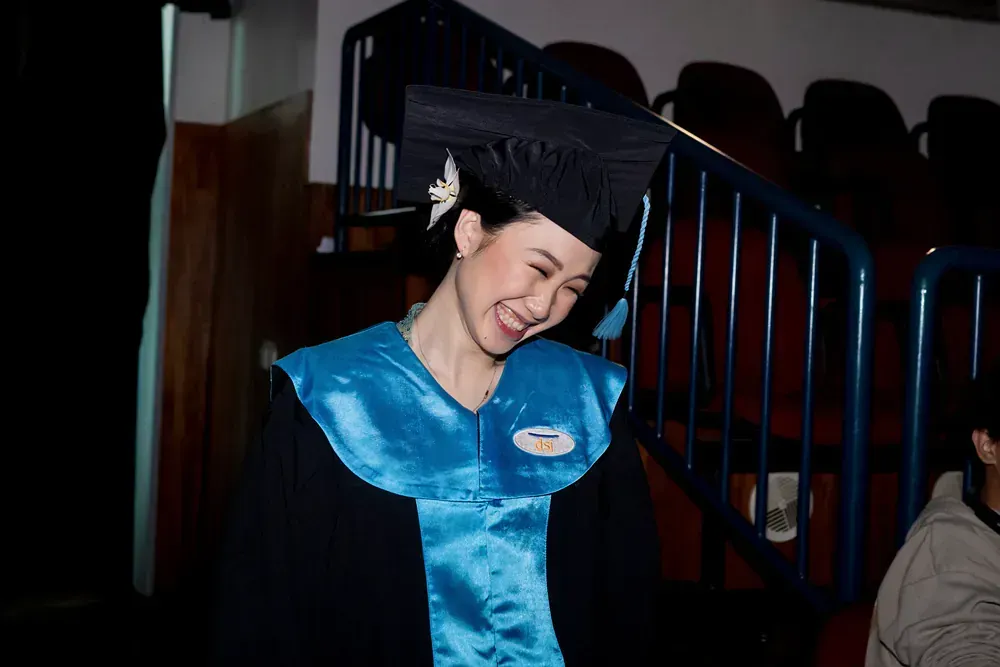 A woman in a graduation cap and gown is smiling.