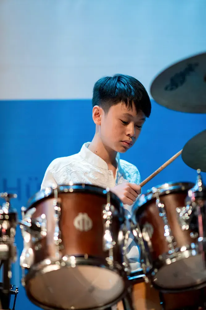 A young boy is playing drums on a stage.