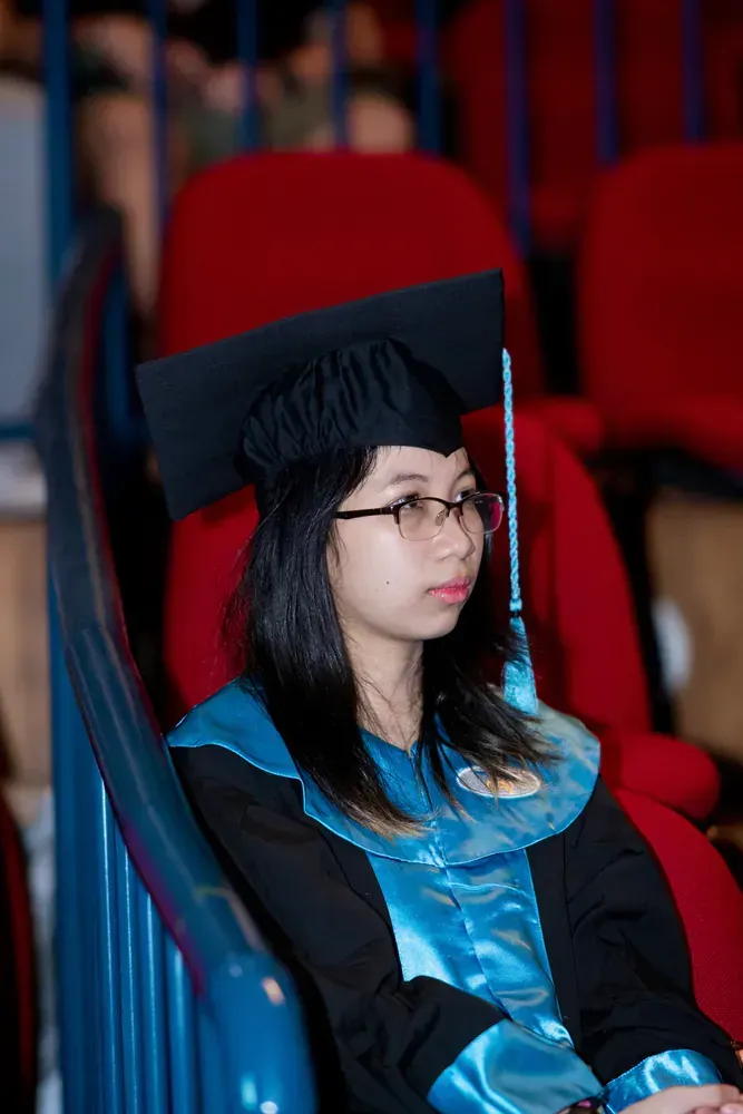 A woman in a graduation cap and gown is sitting in a chair.