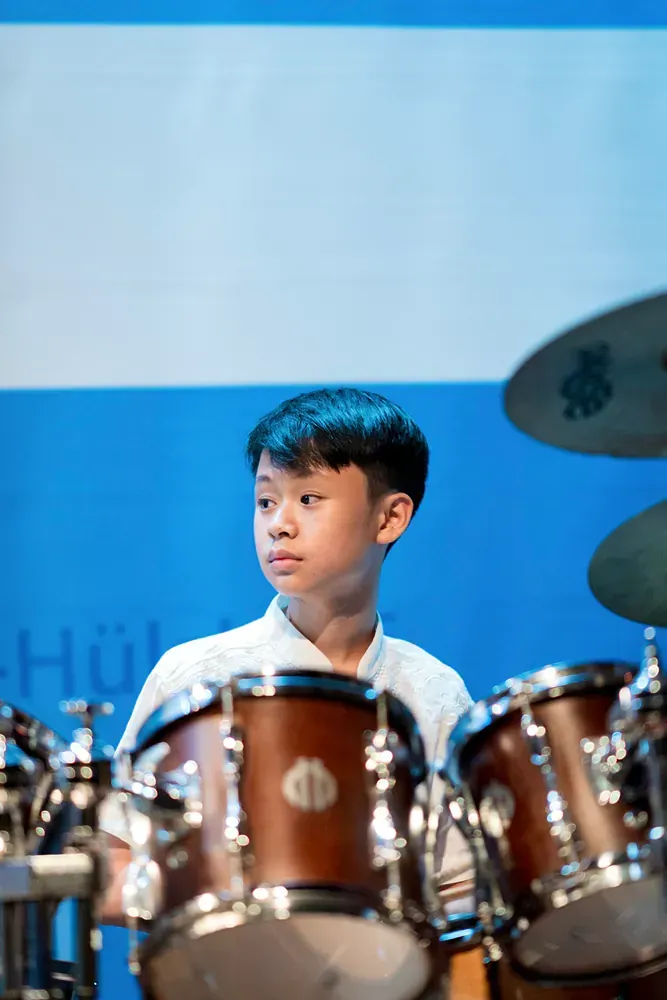 A young boy is playing drums on a stage.