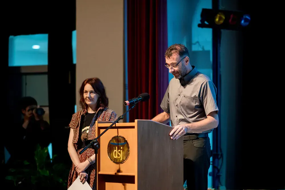 A man and a woman are standing at a podium giving a speech.