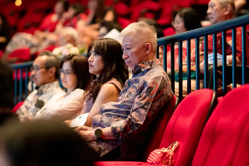 A group of people are sitting in red seats in a theater.
